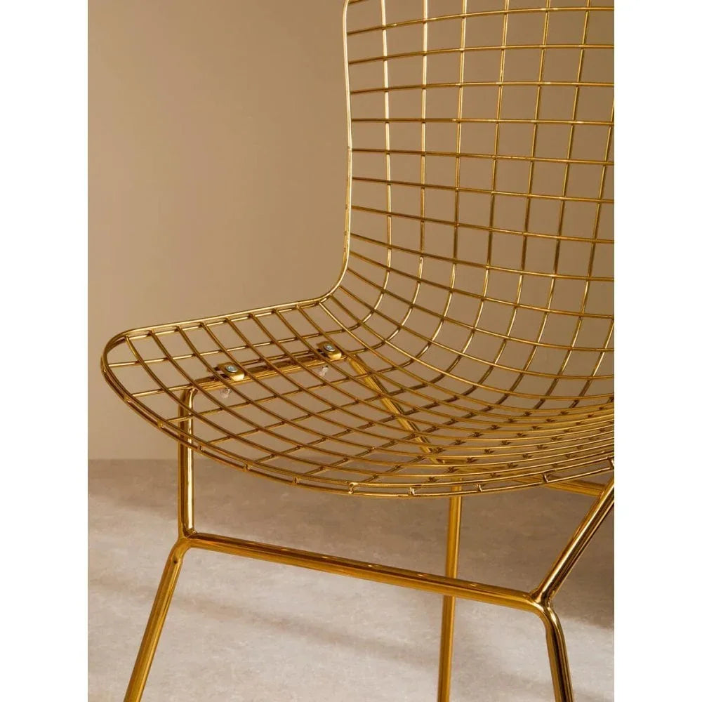 Gold metal wire dining chair with grid backrest and seat, angled view