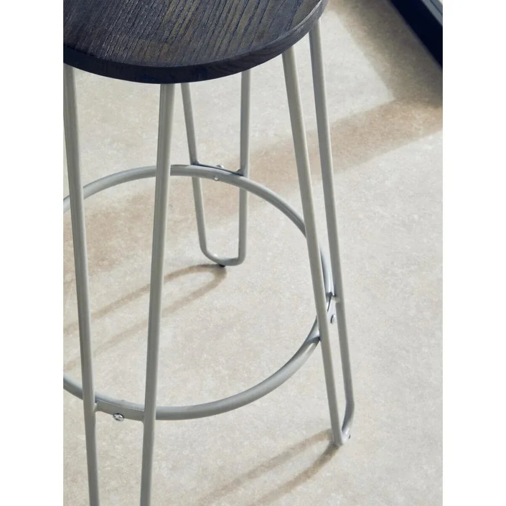 Closeup of bar stool with dark wood seat and grey metal legs on light tile floor