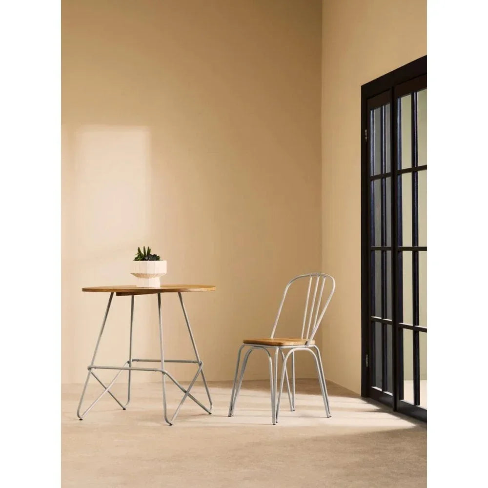 Wood and metal bistro table set with matching chair in a minimalist room