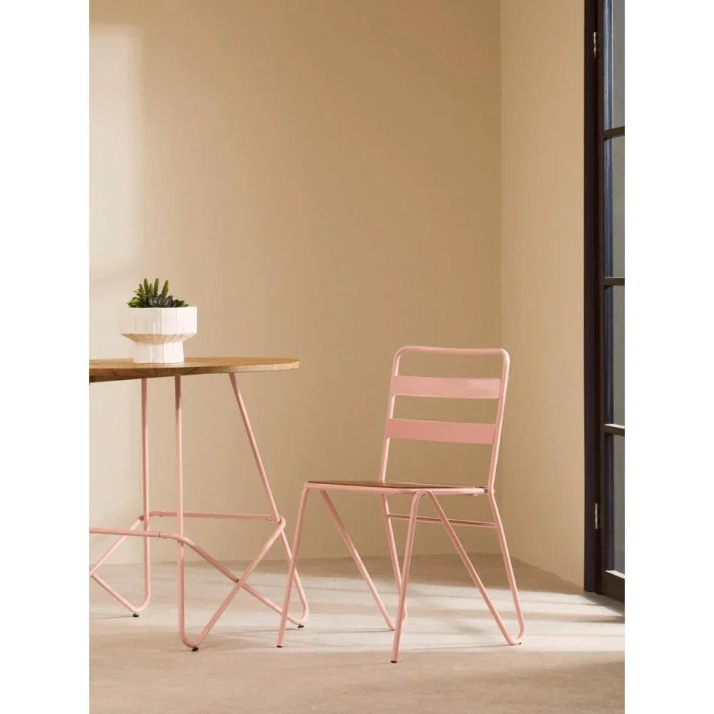 Pink metal dining chair next to wooden table with white planter in modern room