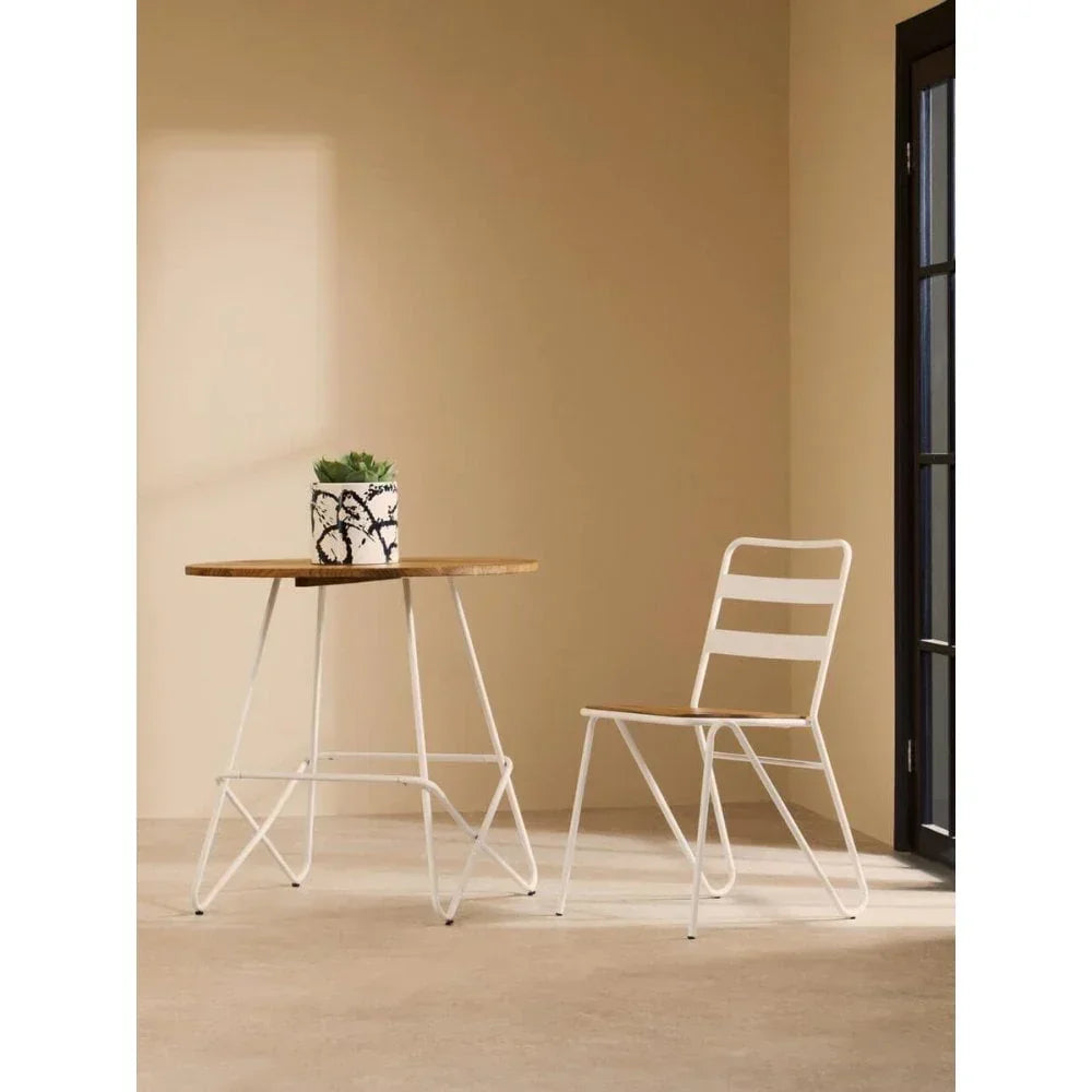 Modern dining set with white metal chair and round wood table with plant indoors