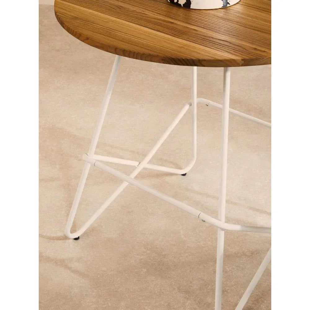 Round wooden side table with white metal frame on beige carpet