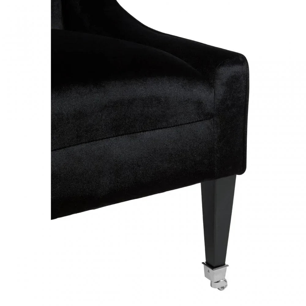 Black velvet sofa corner close-up with tapered wooden leg and chrome castor
