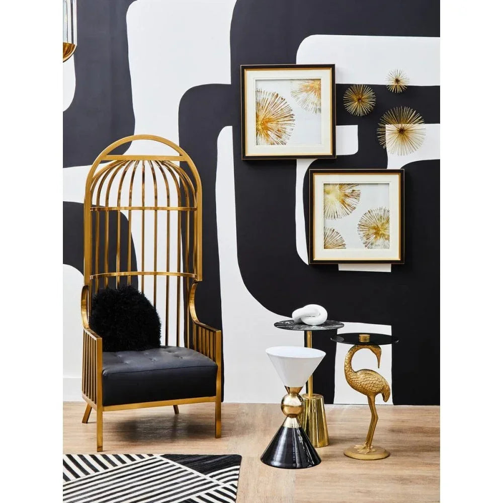Gold metal accent chair with black cushion beside flamingo side table in modern lounge setting