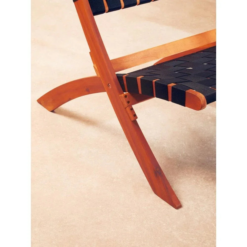 Closeup of wooden chair frame with black woven seat straps on light floor
