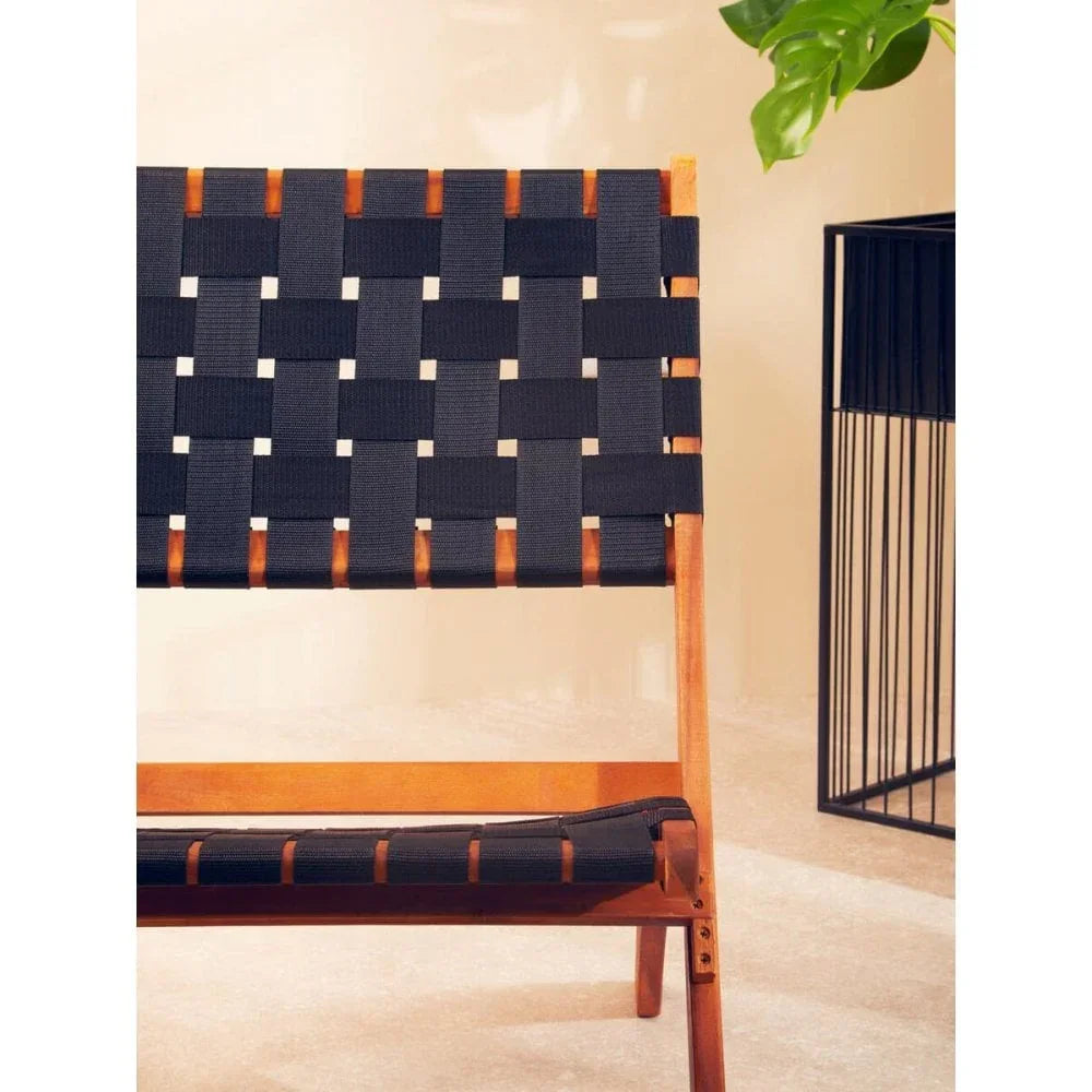 Black webbed wooden lounge chair with modern design against neutral wall