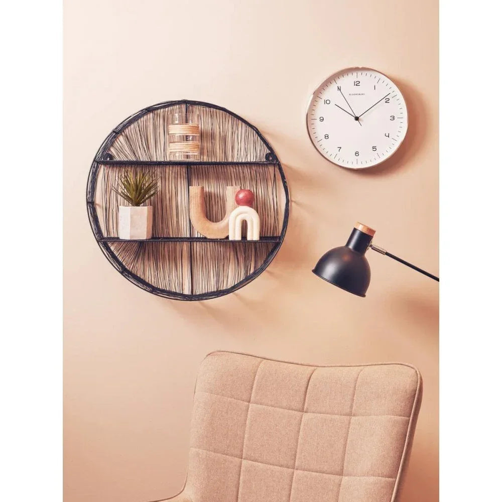 Round wire wall shelf with decor, modern clock, beige chair and black desk lamp