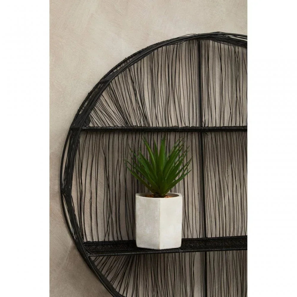 Green faux plant in white geometric pot on black wire wall shelf