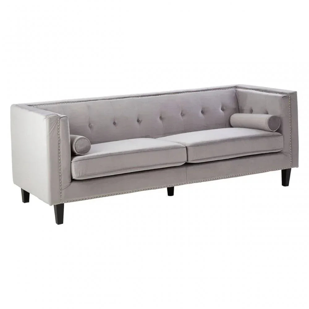 Light grey velvet sofa with button-tufted back, nailhead trim, black legs and bolster cushions