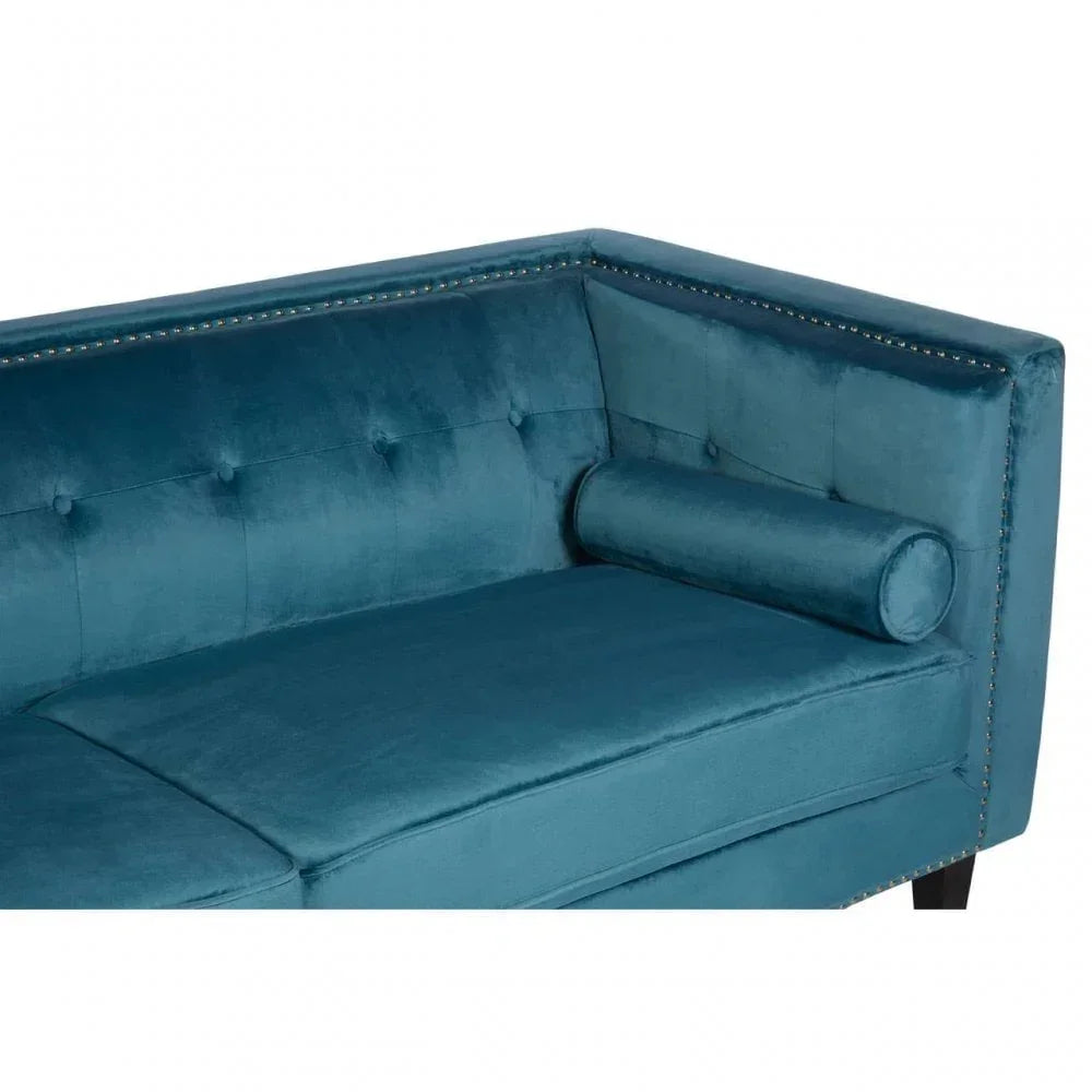 Blue velvet sofa with tufted back, studded trim, and matching bolster cushion, corner angle view