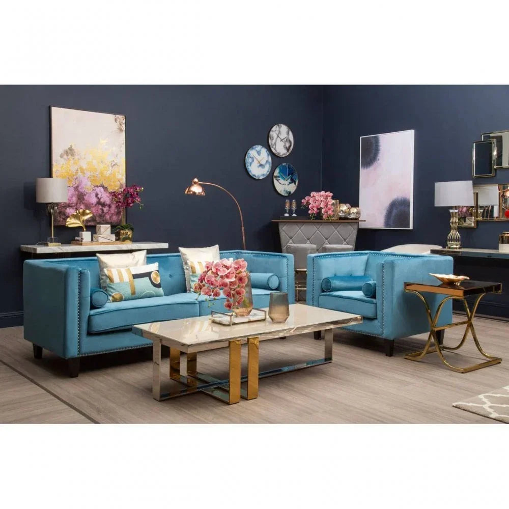 Blue velvet sofas with gold stud trim and marble coffee table in modern living room setting