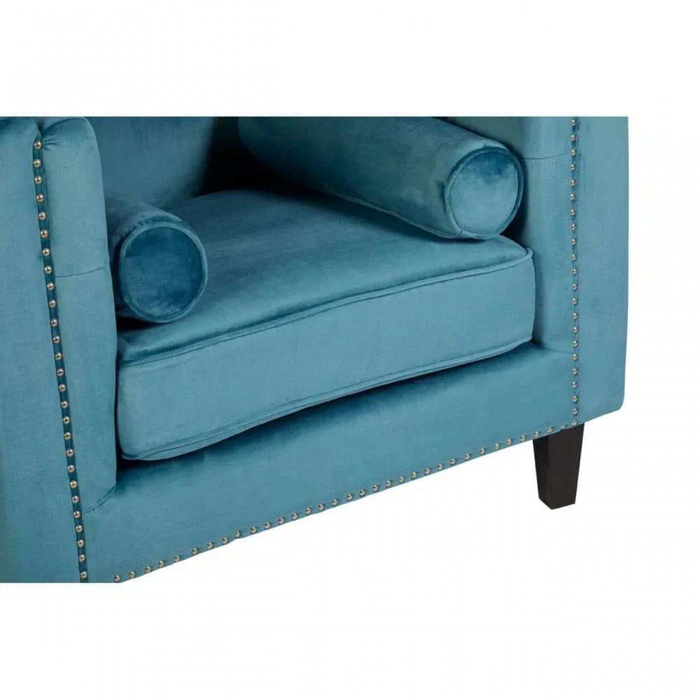 Blue velvet armchair with nailhead trim and matching bolster cushions, angled corner view