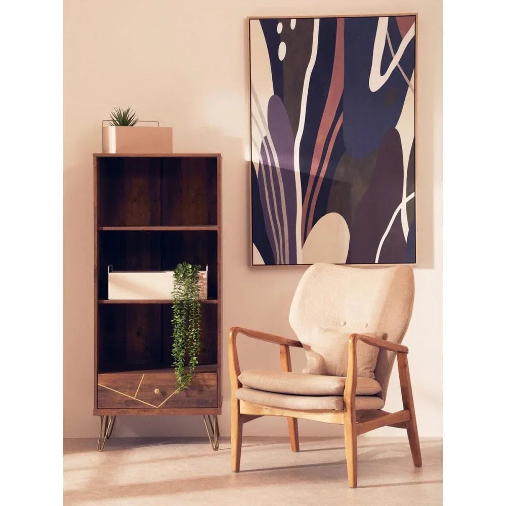 Light wood accent chair with cream cushions beside modern bookcase and abstract wall art