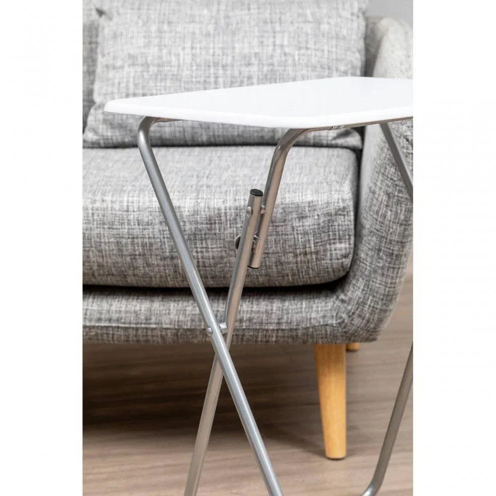 Foldable white tray table with metal legs beside grey fabric sofa on wooden floor