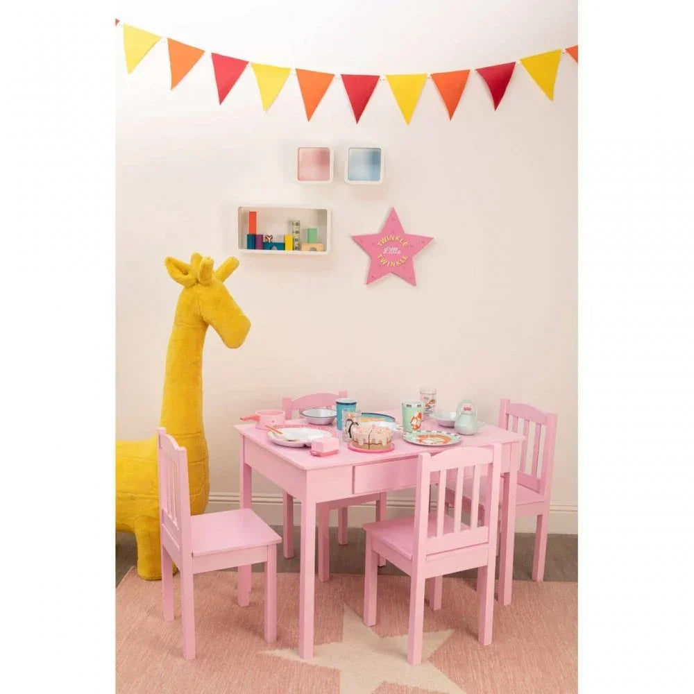 Pink kids table and chairs set with tea party setup in playroom, large plush giraffe nearby