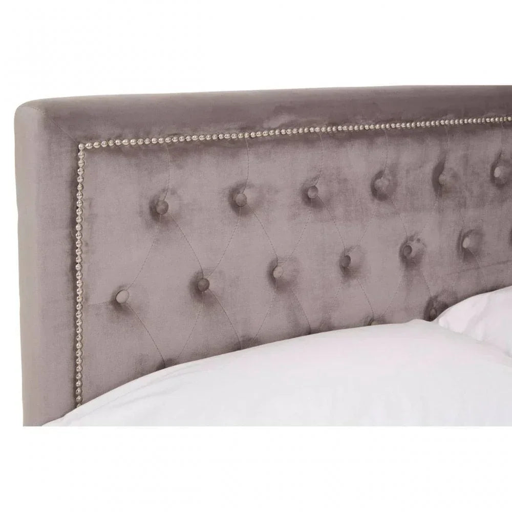 Grey upholstered bed headboard with button tufted design and metallic stud detailing