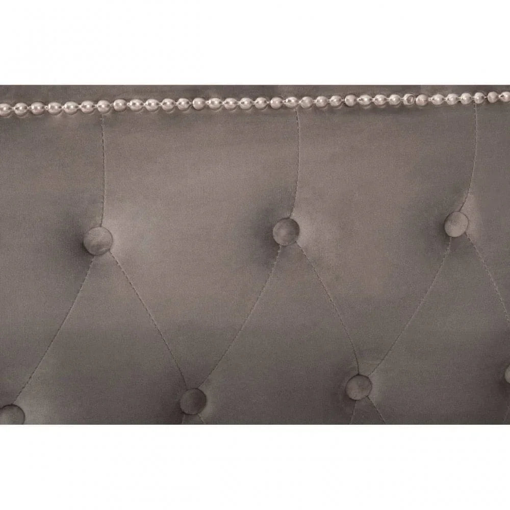 Grey velvet bed headboard with button tufting and silver stud trim close-up
