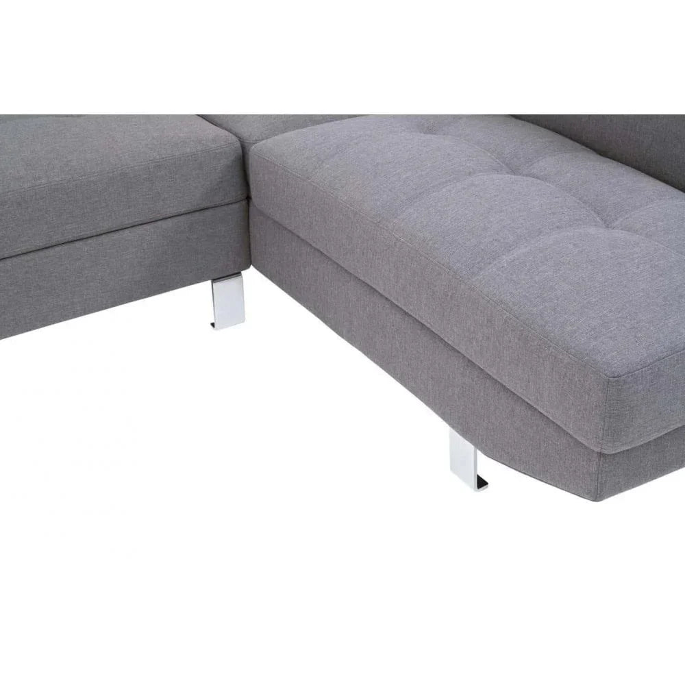 Closeup of grey fabric corner sofa with chrome legs and tufted seat detail