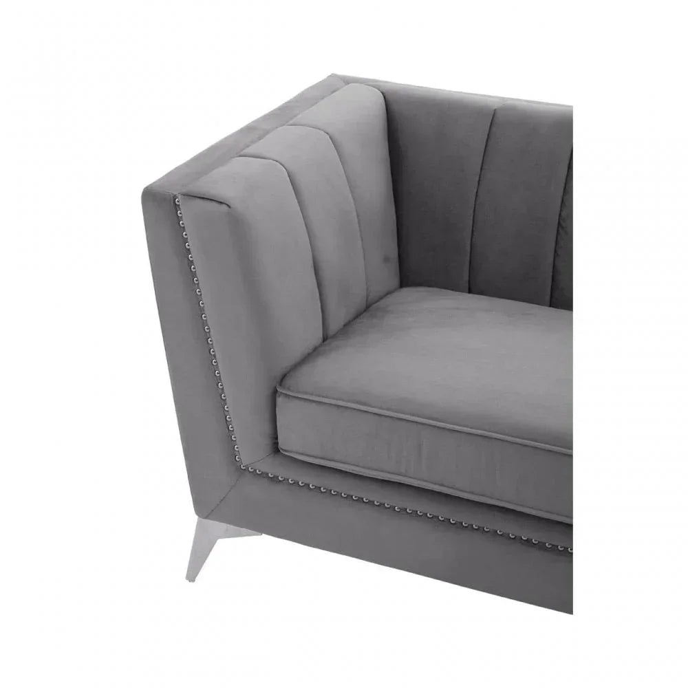 Grey velvet sofa corner with studded trim and angled metal leg