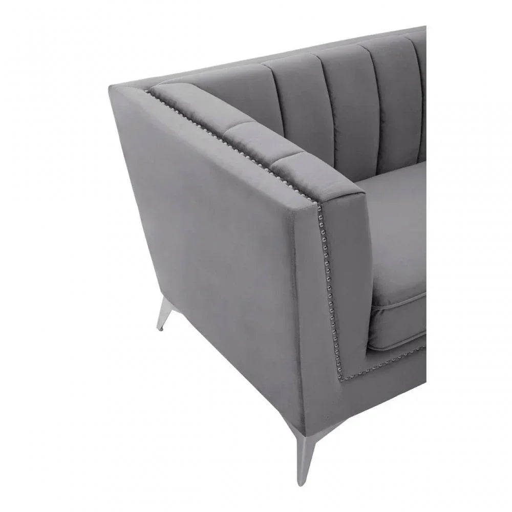 Grey velvet sofa arm with vertical channel tufting and chrome stud detailing