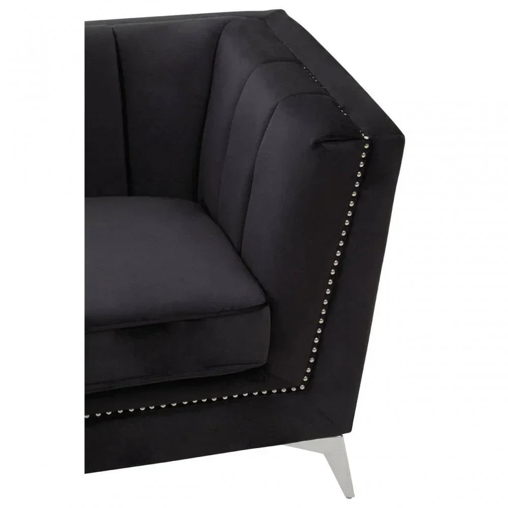 Black velvet sofa corner with silver stud detailing and chrome leg, close-up view