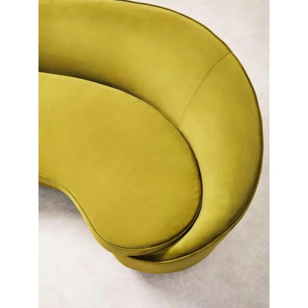 Curved mustard yellow velvet sofa seat cushion top view on light carpet
