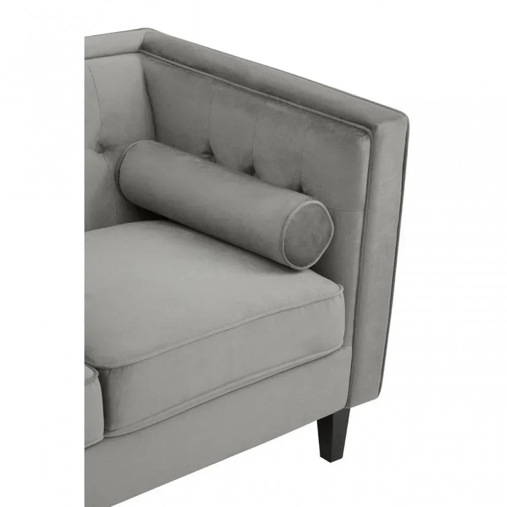 Grey velvet sofa corner with bolster cushion and button-tufted backrest detail