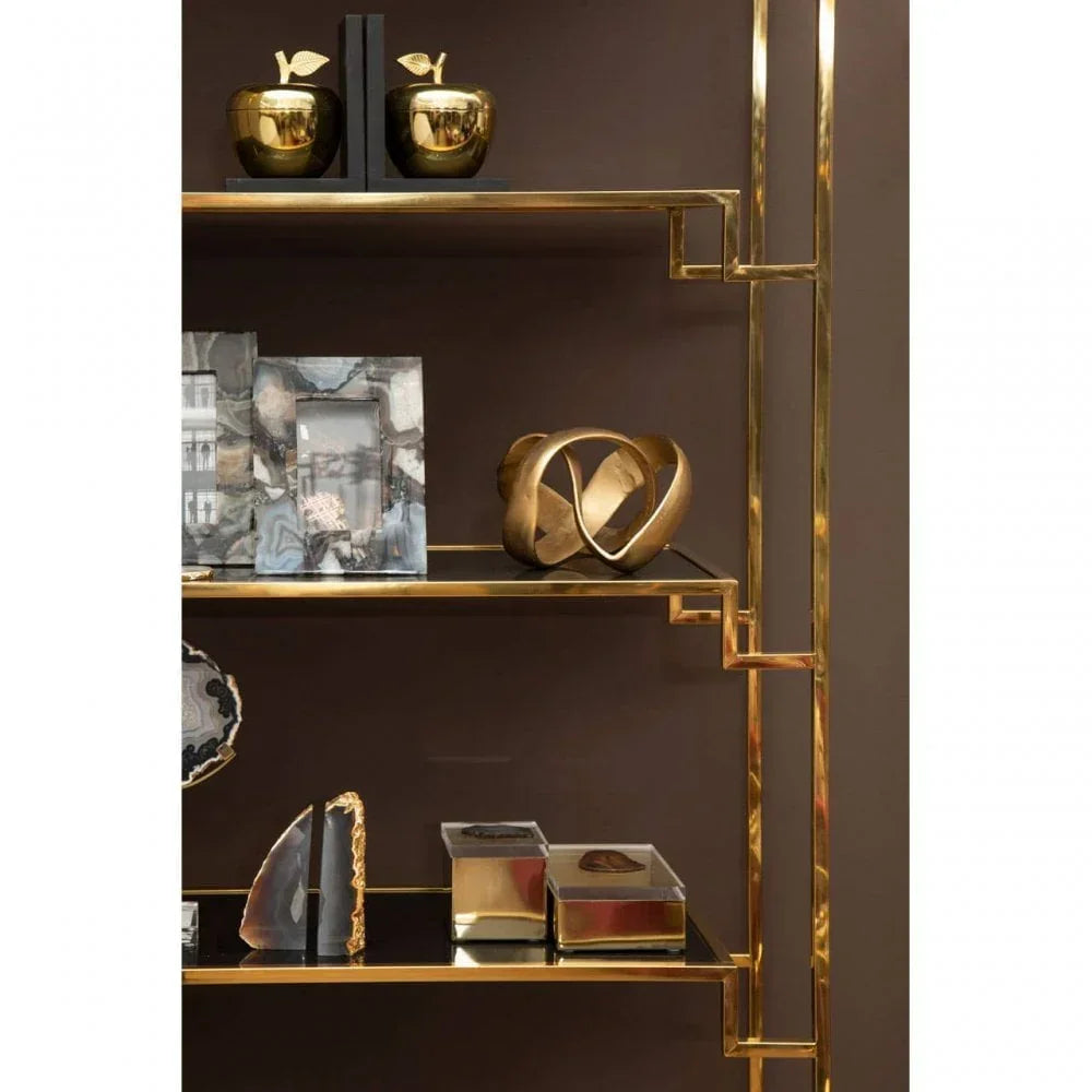 Gold metal shelving unit with decorative objects, photo frames, and sculptural accents