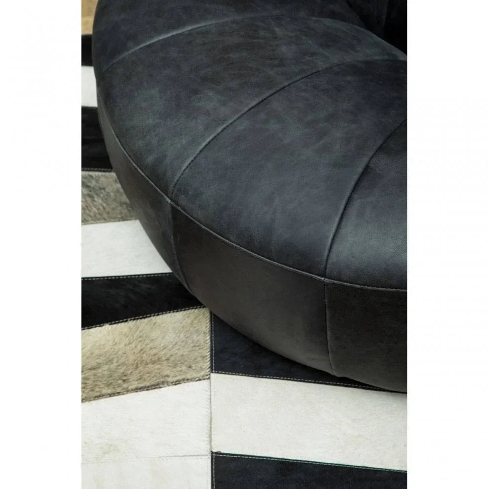 Close-up of black leather sofa seat with patterned rug underneath