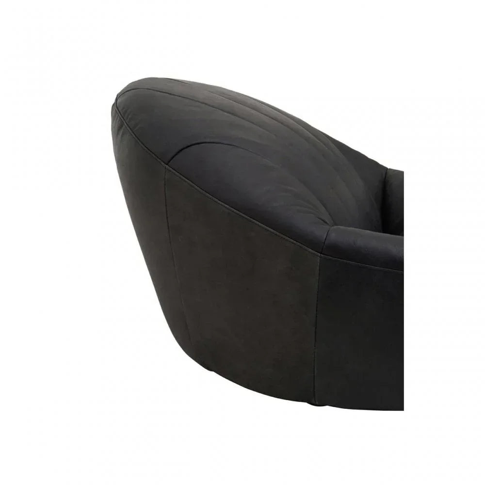Close-up of black velvet armchair with curved backrest and stitched detail