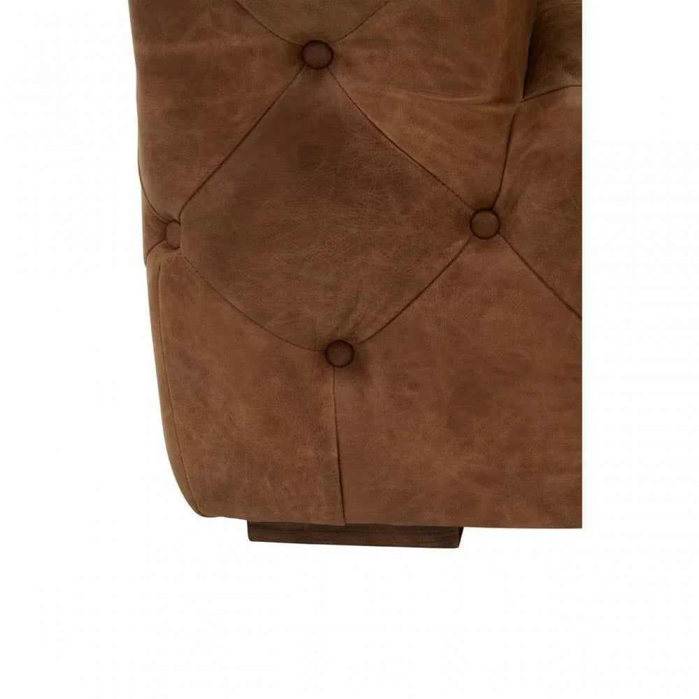 Closeup of brown leather sofa with deep button tufting and wood base