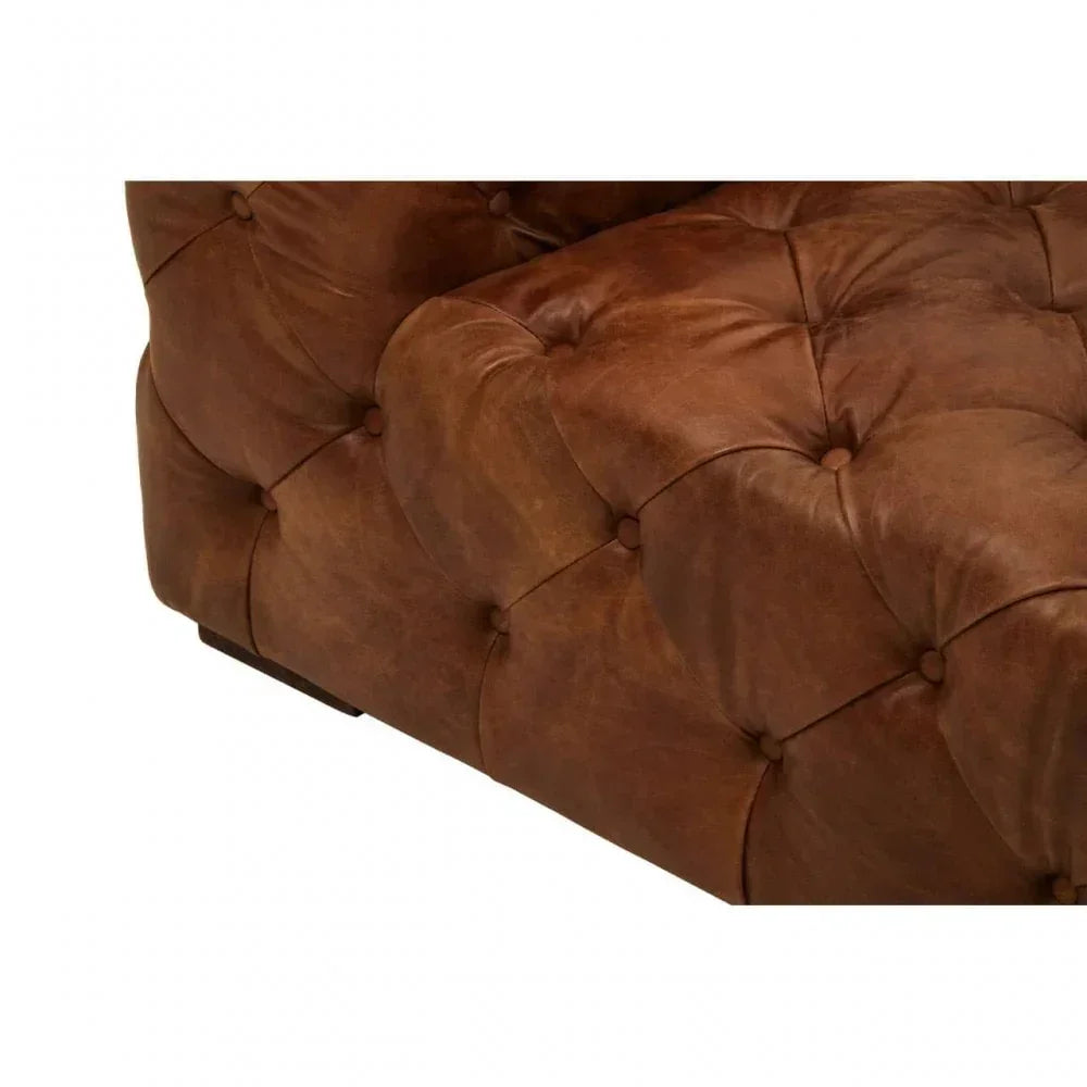 Close-up of brown leather Chesterfield sofa arm with deep button tufting