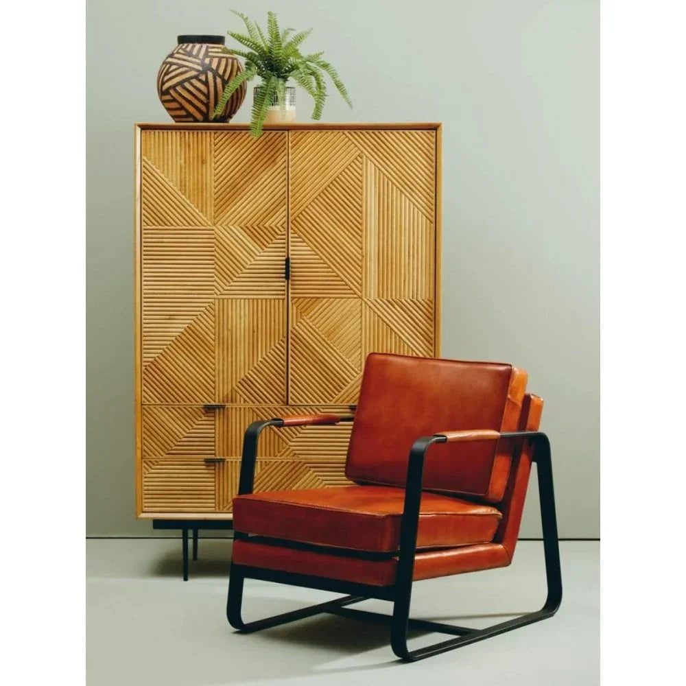 Tan leather armchair with black metal frame beside geometric wood cabinet