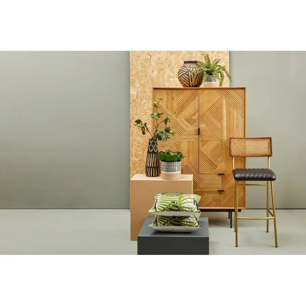 Rattan cabinet with geometric pattern, bar stool, decorative vases, and green cushions
