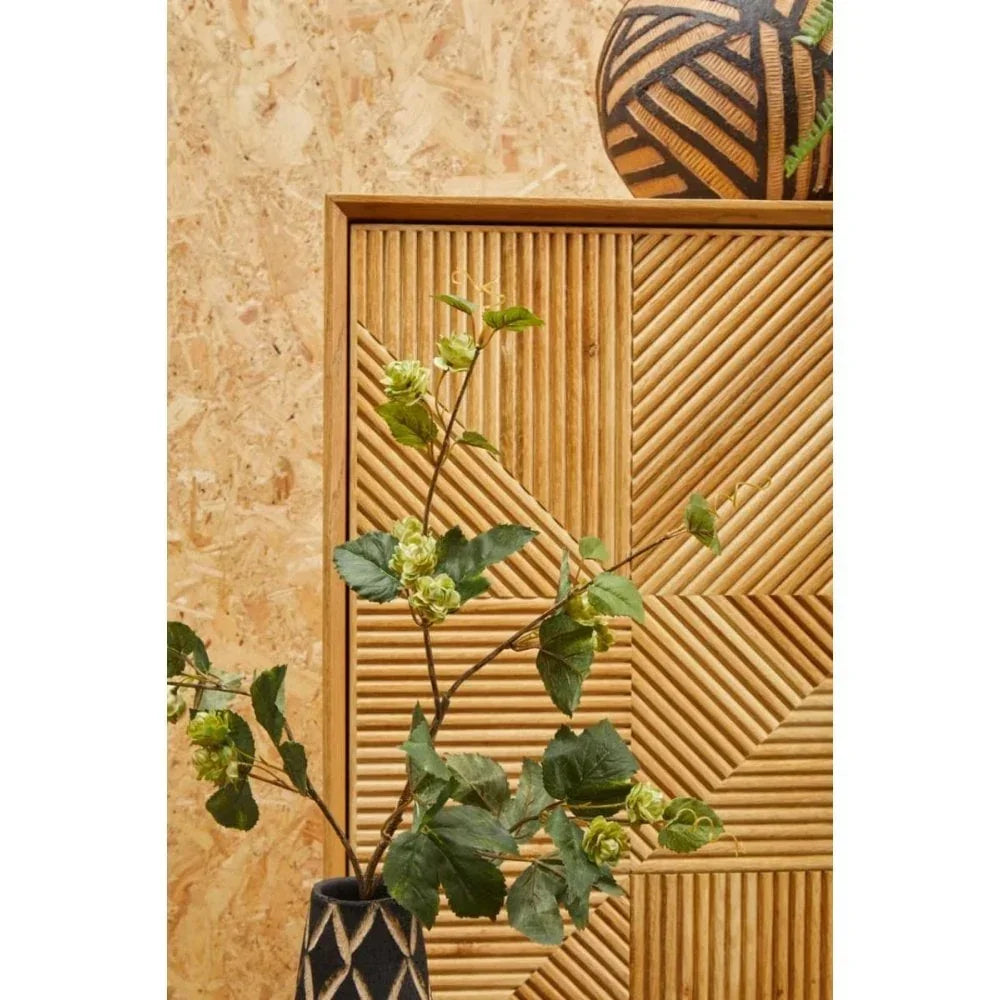 Geometric wood sideboard with textured panel, decorative vase and green foliage, close view