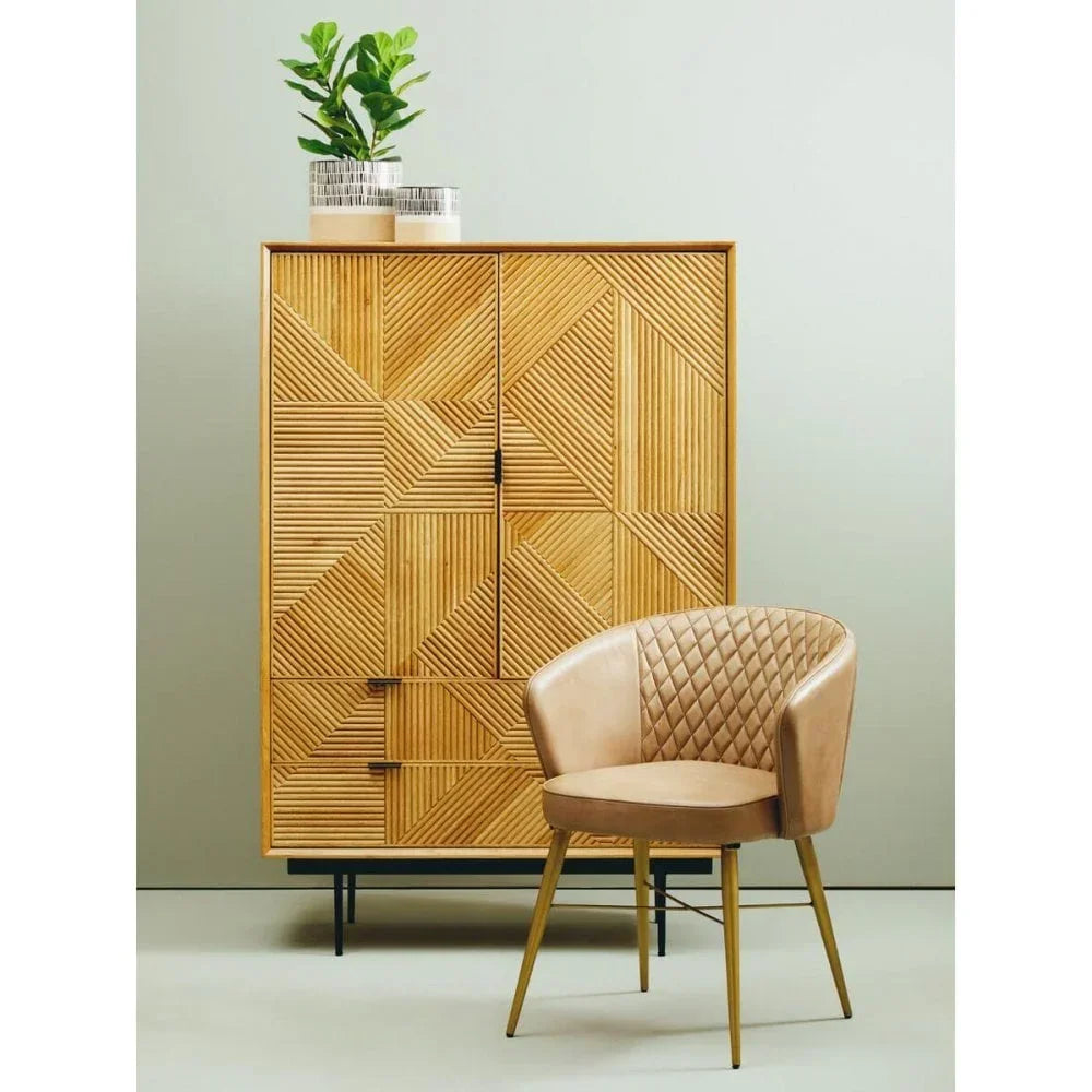 Patterned wooden cabinet with metal legs and tan quilted accent chair against pale wall
