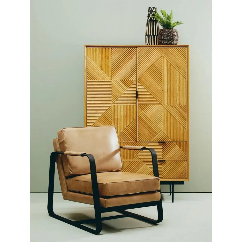 Tan leather armchair with black frame beside geometric wood cabinet and decorative vases