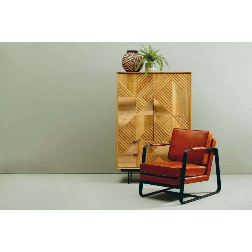 Brown leather accent chair with black metal frame beside geometric wood sideboard