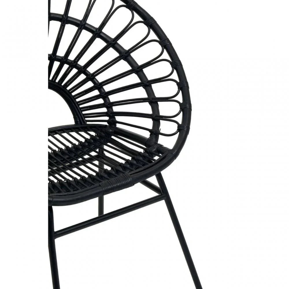 Close up of black rattan dining chair with curved back and metal legs