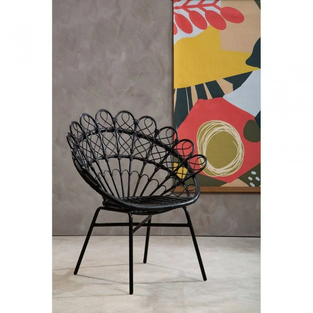Black rattan accent chair with metal legs set against grey wall and abstract art