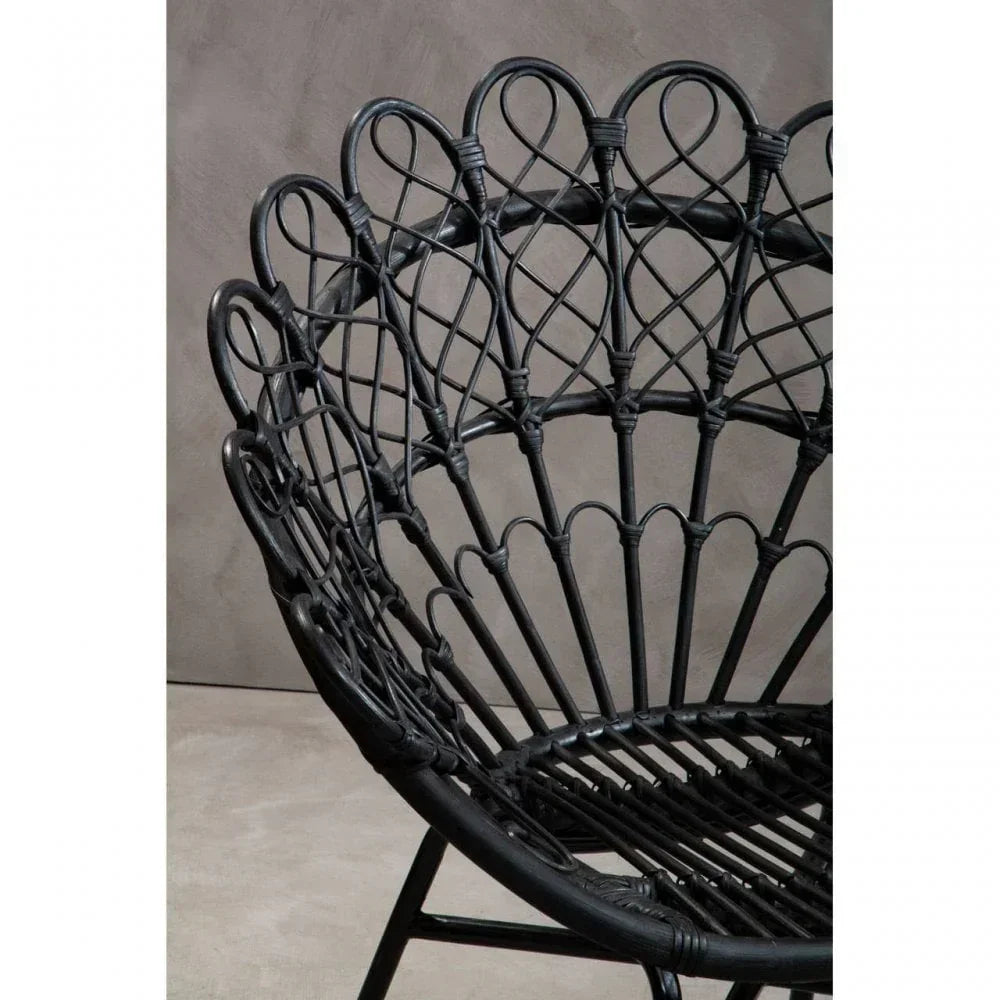 Close-up of black rattan chair with decorative backrest design and curved frame