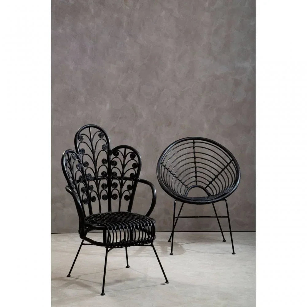 Black rattan accent chairs with intricate detailing, set against a neutral textured wall