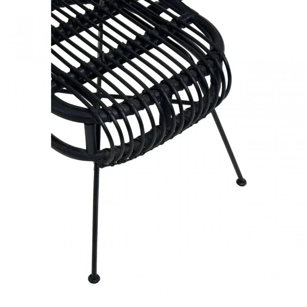 Close view of black rattan chair seat with slender metal legs and curved design