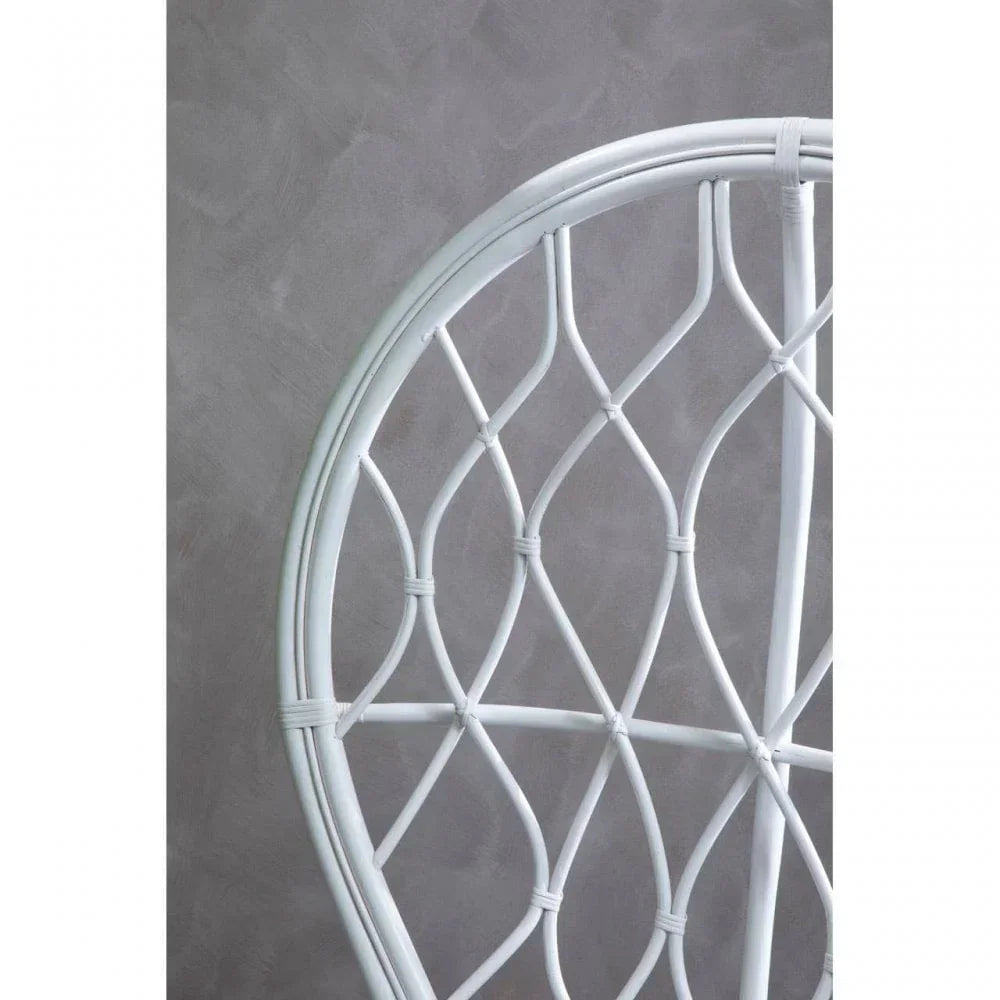 White rattan chair back with curved woven pattern against grey wall
