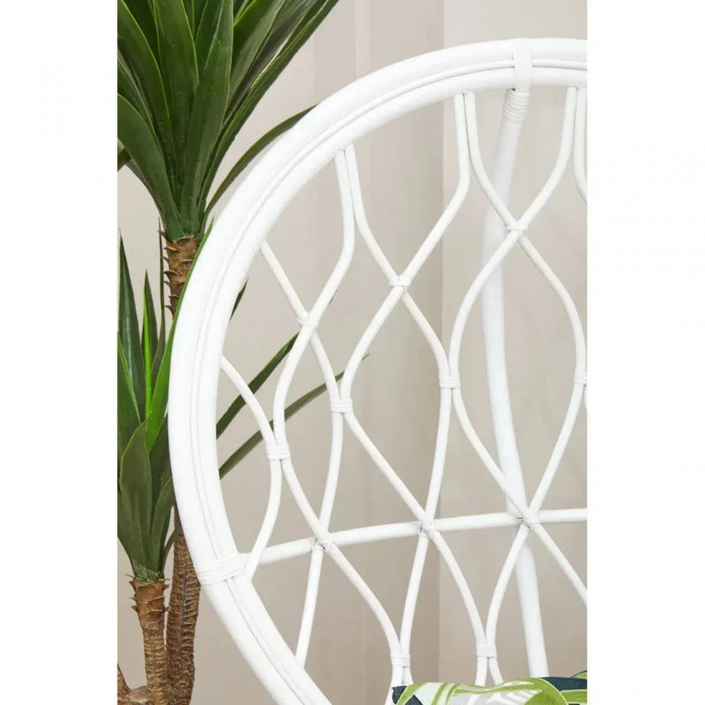 White rattan chair with geometric backrest design beside indoor potted plant