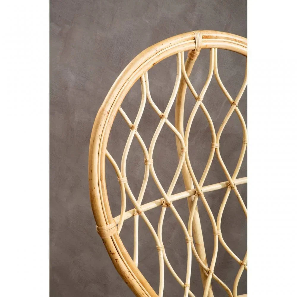 Closeup of natural rattan chair backrest with woven lattice pattern against grey wall