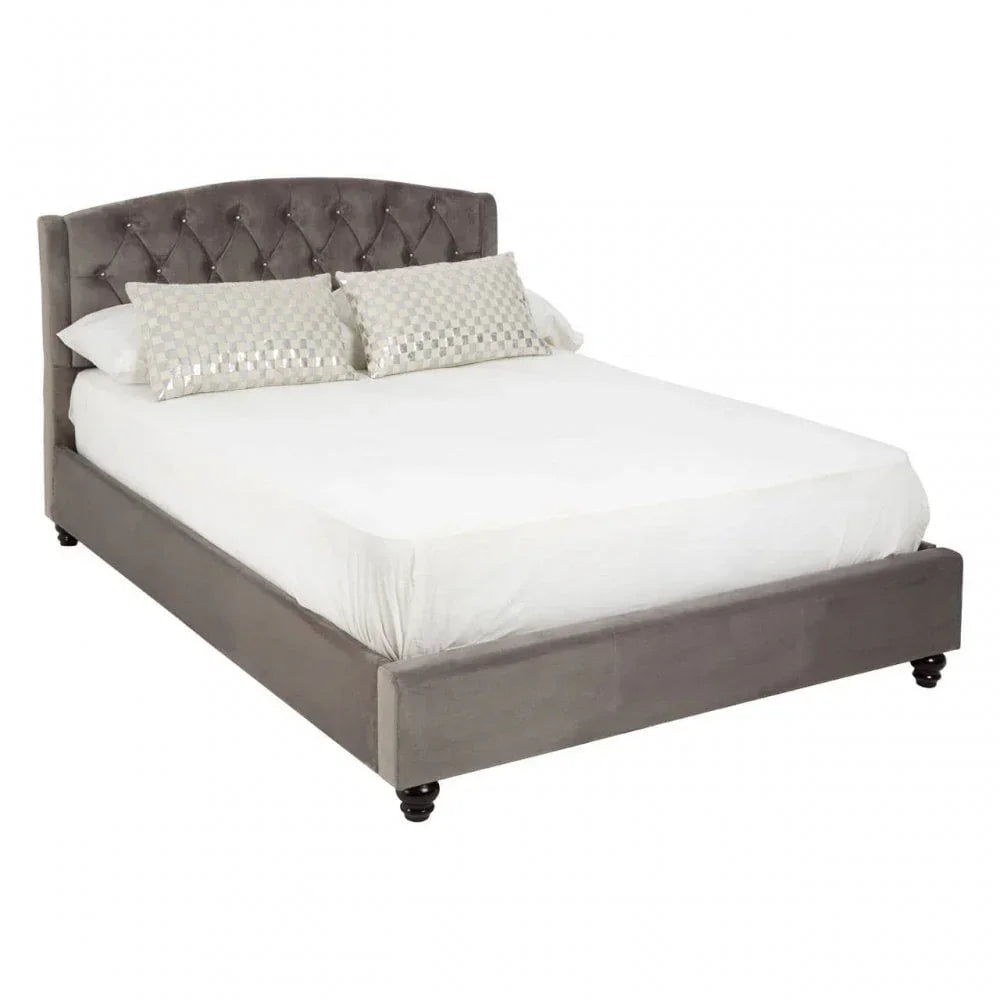 Grey upholstered bed frame with diamond-tufted headboard and two decorative pillows