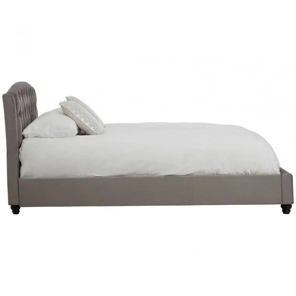 Side view of upholstered bed frame with tufted headboard and white bedding
