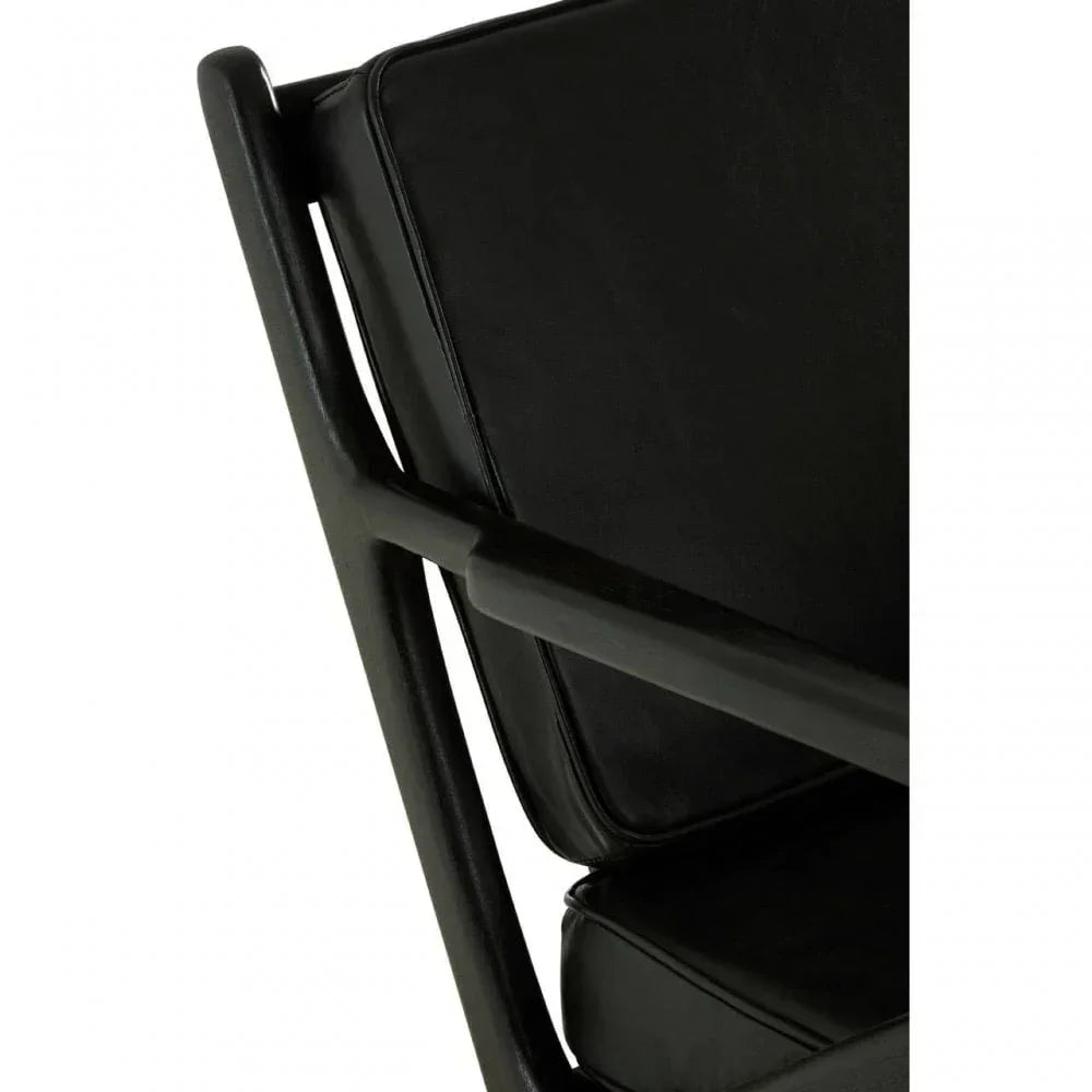 Closeup of black leather armchair with angled wooden frame and seat cushion