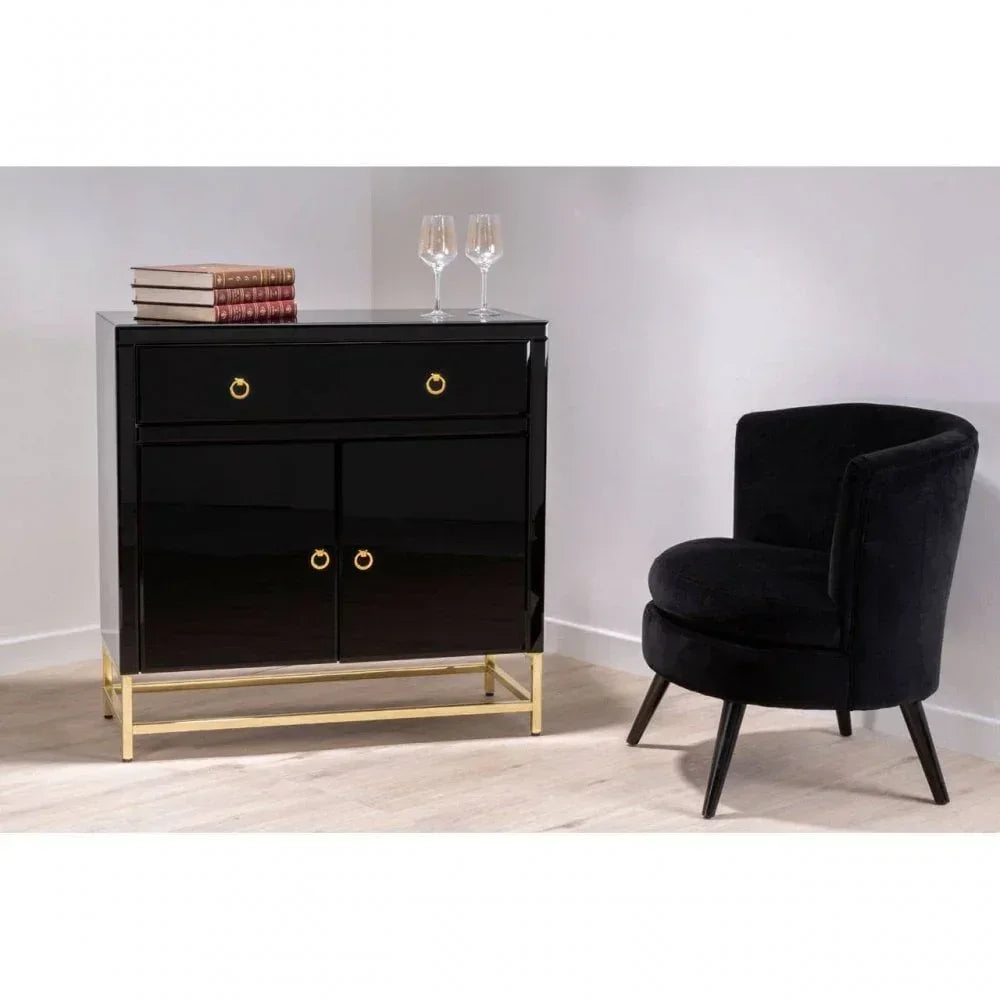 Black sideboard with gold handles and base, paired with velvet accent chair in modern room
